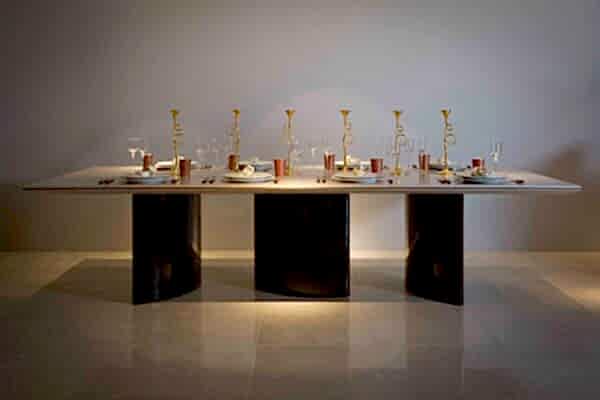 A luxury modern dining room table with a festive table setting, including holiday-themed cutlery and plates.